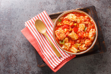 Cod stew with vegetables peppers, tomatoes, garlic and onions close-up in a bowl on the table. Horizontal top view from above