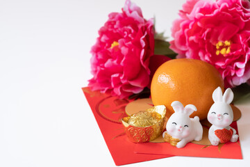 Chinese New Year of the rabbit festival concept. Oorange, red envelopes, two rabbits and gold ingot decorated with plum blossom on white background. 