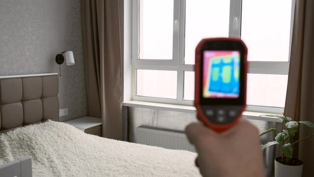 Inspection of a window block inside the room with a thermal imager, searching for heat loss in a building. Thermography concept