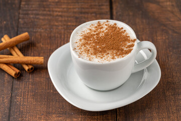 Cinnamon sprinkled salep in a white cup on wooden table