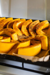 Big baking plate full of pumpkin slices sprinkled with spices