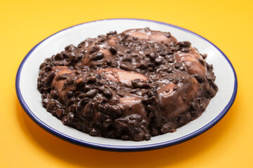 black beans stew with sausages on a white dish