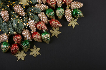 Green branches of a Christmas tree with decorations in the form of golden, red, green cones and...