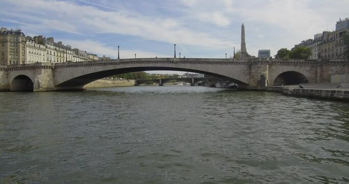 Bateau-mouche sailing on the Seine and passing under the Pont de la Tournelle and its Statue de Sainte Genevi&egrave;ve toward the Pont de Sully in Paris.