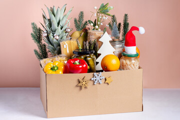 Canned food, pasta, fruits and vegetables in a box for donation decorated for Christmas, charity...