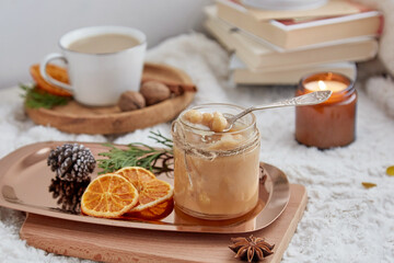 Christmas cozy breakfast. Homemade hazelnut salted caramel spread in glass jar, candles, books and cup of coffee