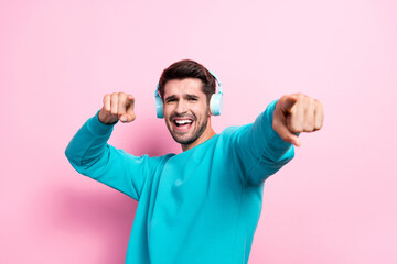 Photo of funny active energetic motion dancing listen music loud wireless headphones finger direct pick you party isolated on pink color background