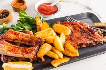 Front view of the dish with pork ribs and grilled potatoes. juicy delicious lunch or dinner. menu.