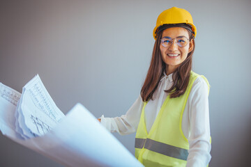 A portrait of a young female engineer looking at the camera on a construction site. Beautiful asian woman engineer and safety helmet on gray background, construction concept, Engineer, Industry.