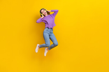 Fototapeta na wymiar Full length photo of excited carefree person jumping hands touch wireless headphones isolated on yellow color background