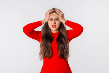 Portrait of the shocked anxious young woman in panic, holding hands on head and worrying, standing...