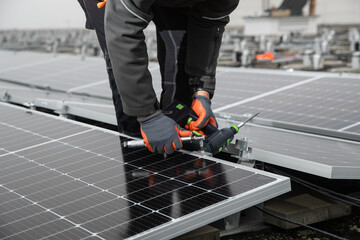 Worker installing solar photovoltaic panel system on roof of a building.