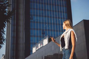 Fototapeta na wymiar Young blonde woman in an urban setting using a mobile device