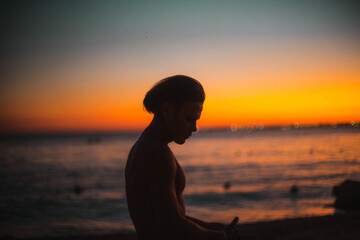 silhouette of a man with a naked torso at sunset by the sea. long haired man.