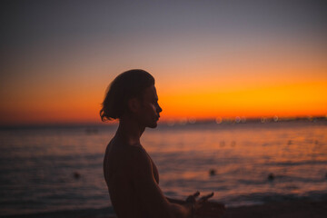 silhouette of a man with a naked torso at sunset by the sea. long haired man.