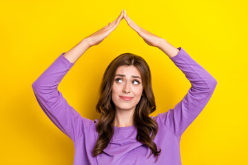 Fototapeta na wymiar Photo of unsatisfied lady curly hair wear purple shirt hands up roof symbol home protection problems look mockup isolated on yellow color background