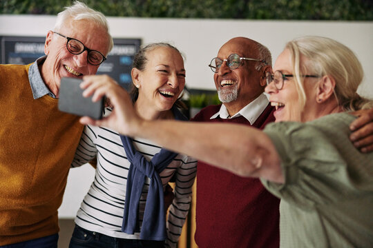 Group of laughing seniors taking selfies