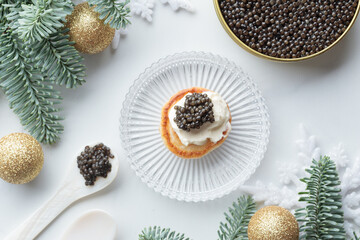 Black caviar appetizers mini pancake on a christmas decorated white background