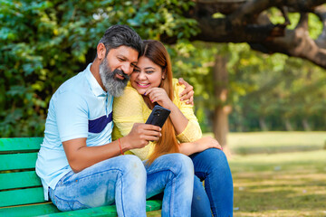 Fototapeta premium Indian man and woman watching some detail in smartphone at park.