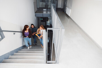 View from the top of the stairs, three female students coming up the stairs