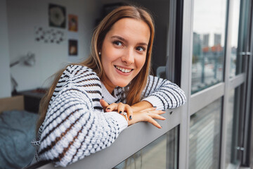 Smiling woman student looking out her dorm room window