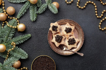 Black caviar appetizers stars on a christmas decorated black table