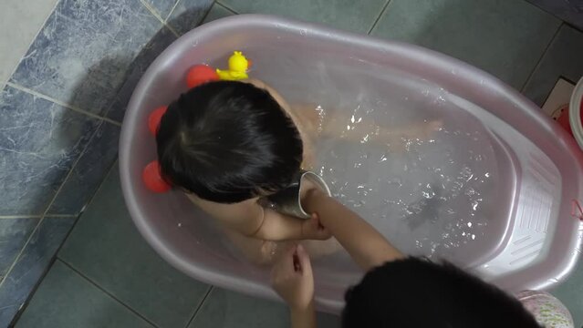Top down view sister play the rubber shark toy with little brother at baby bathtub