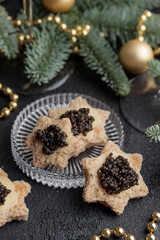 Black caviar appetizers stars on a christmas decorated black table