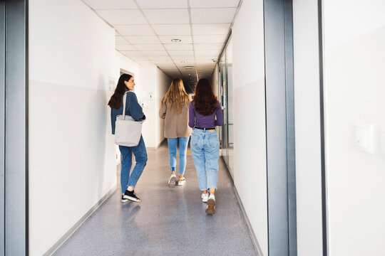 View From The Back Three Friends Walking In The Hallway, Searching For Their Classroom