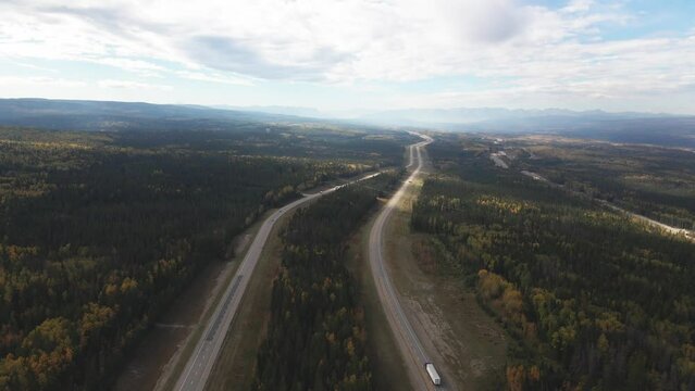 Impressive Scene with an infinite View of the Yellowhead Highway 5 in Alberta ,Canada with Cars and Trucks driving on the Road on a partially cloudy day in the fall