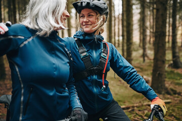 Smiling mother and daughter going mountain biking in the woods
