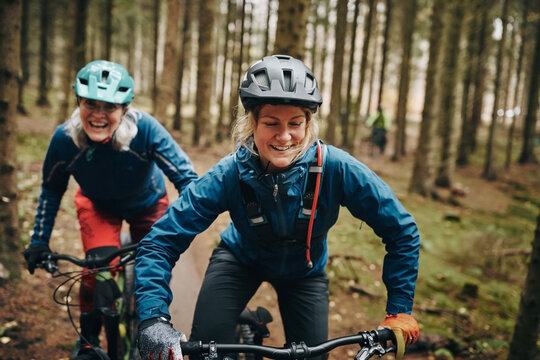 Smiling woman mountain biking with her mom in a forest