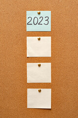 Blank paper notes are pinned to a cork board. Inscription 2023. The concept of detective...