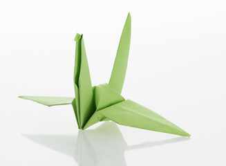 Green origami paper crane on white background