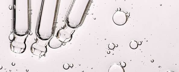 Three pipettes and a serum texture for skin with bubbles. Liquid body care product. Closeup.