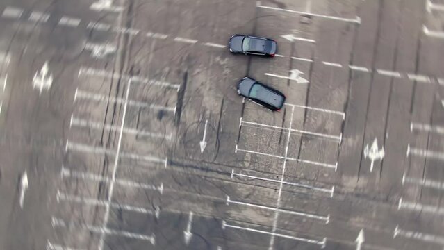 Aerial view of driver drifting on sport car making circles on empty parking