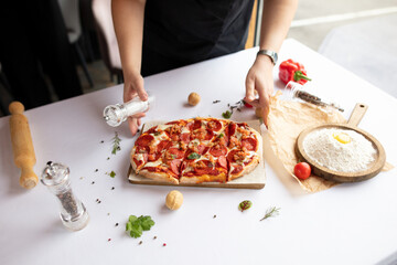 Serving hands of a pizza chef with vegetables