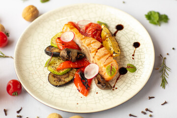 Dish red fish with vegetables on a white background.
