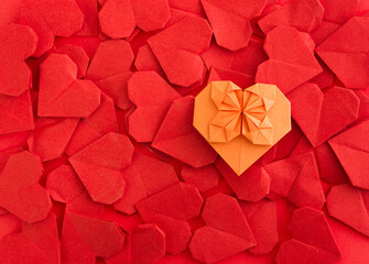 Orange origami heart on red origami hearts