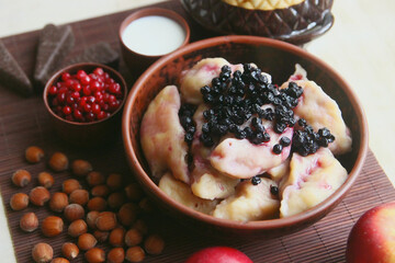 Ukrainian dumplings with blueberries. Still life with apples, candies, nuts.