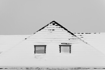 Architecture. The roof of the house is covered with snow. Tiling. Window. Winter, January, February, December. Cloudy. Black and white image