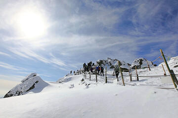 추운 겨울에 눈 덮인 높은 산을 오르는 사람들