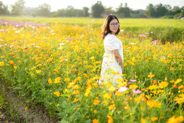Fototapeta premium Portrait of asian Young woman happy traveler with white dress enjoying in Yellow and pink sulfur Cosmos flowers blooming field in the nature garden of in Chiang Mai,Thailand,travel relax vacation