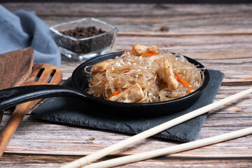 Funchosa glass noodles from green beans fried in a frying pan with chicken