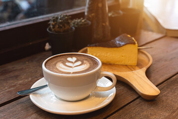 Hot coffee latte with latte art milk foam in cup mug and Homemade chocolate cake wood desk on wood desk on top view. As breakfast In a coffee shop at the cafe,during business work concept