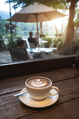 Hot coffee latte with latte art milk foam in cup mug on wood desk on top view. As breakfast In a coffee shop at the cafe, during business work concept