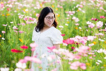 Portrait of asian Young woman happy traveler with white dress enjoying in Yellow and pink sulfur Cosmos flowers blooming field in the nature garden of in Chiang Mai,Thailand,travel relax vacation