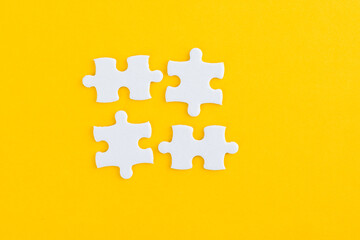 Four puzzle pieces on yellow background