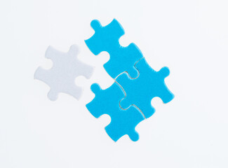 Fototapeta premium Three blue and one white puzzle pieces on white background