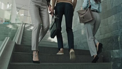 Low angle view of office workers walking down and up the stairs during working day in office